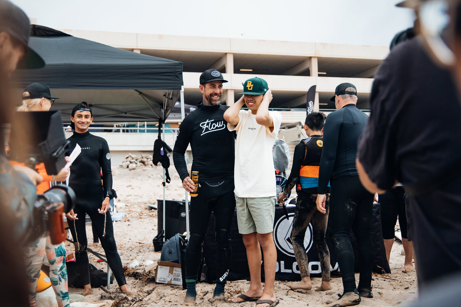 Pat laughing with a young athlete at a Flow tent on the beach